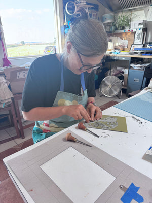Participant carving a detailed lino block by hand during a Mustard & Gray linocut printing workshop in the Shropshire countryside studio.