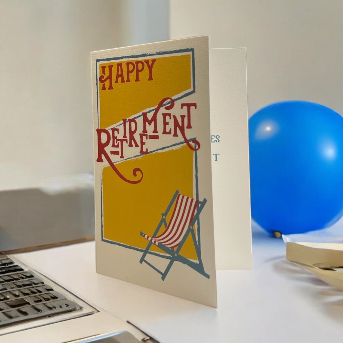 a happy retirement card sitting on a desk next to a laptop