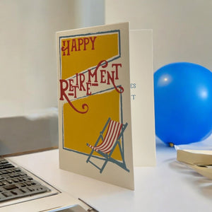 a happy retirement card sitting on a desk next to a laptop