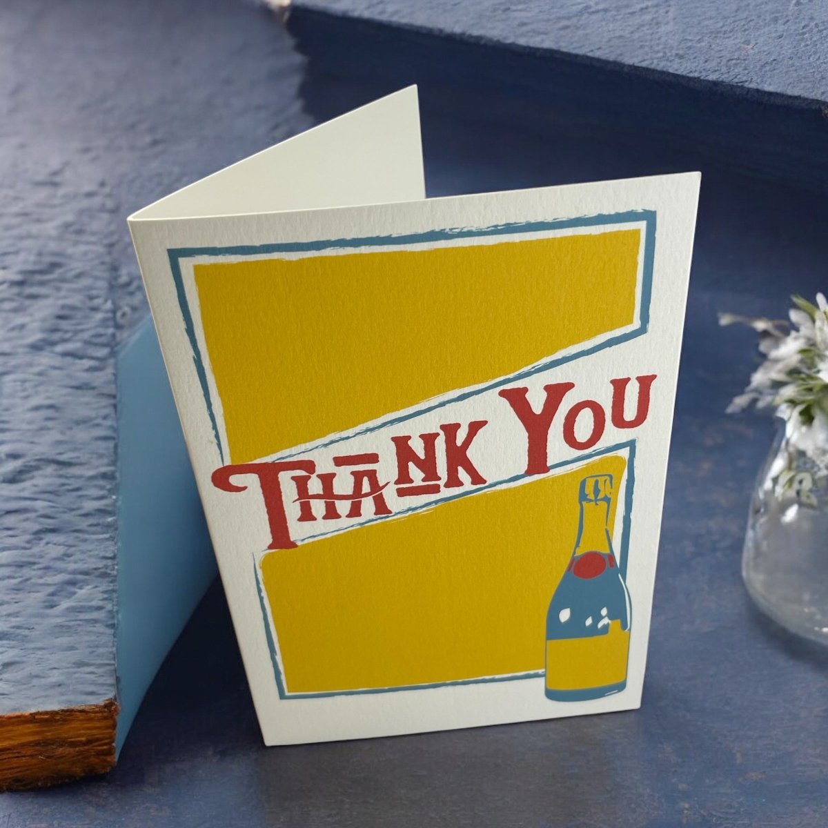 a thank you card sitting on a table next to a vase of flowers