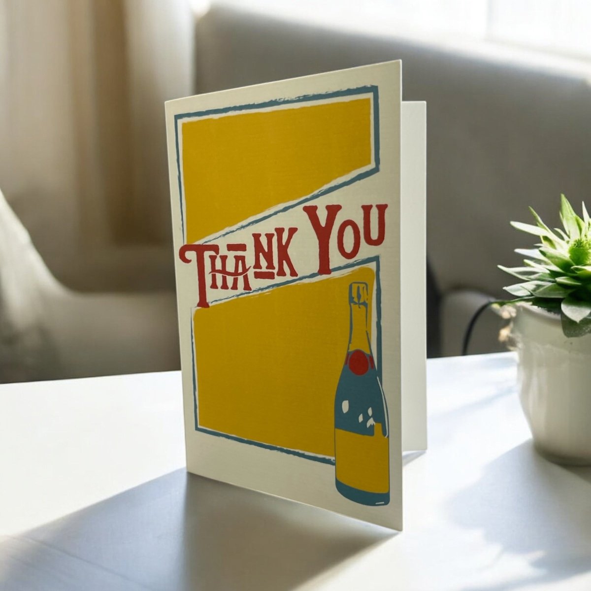 a thank you card sitting on a table next to a potted plant