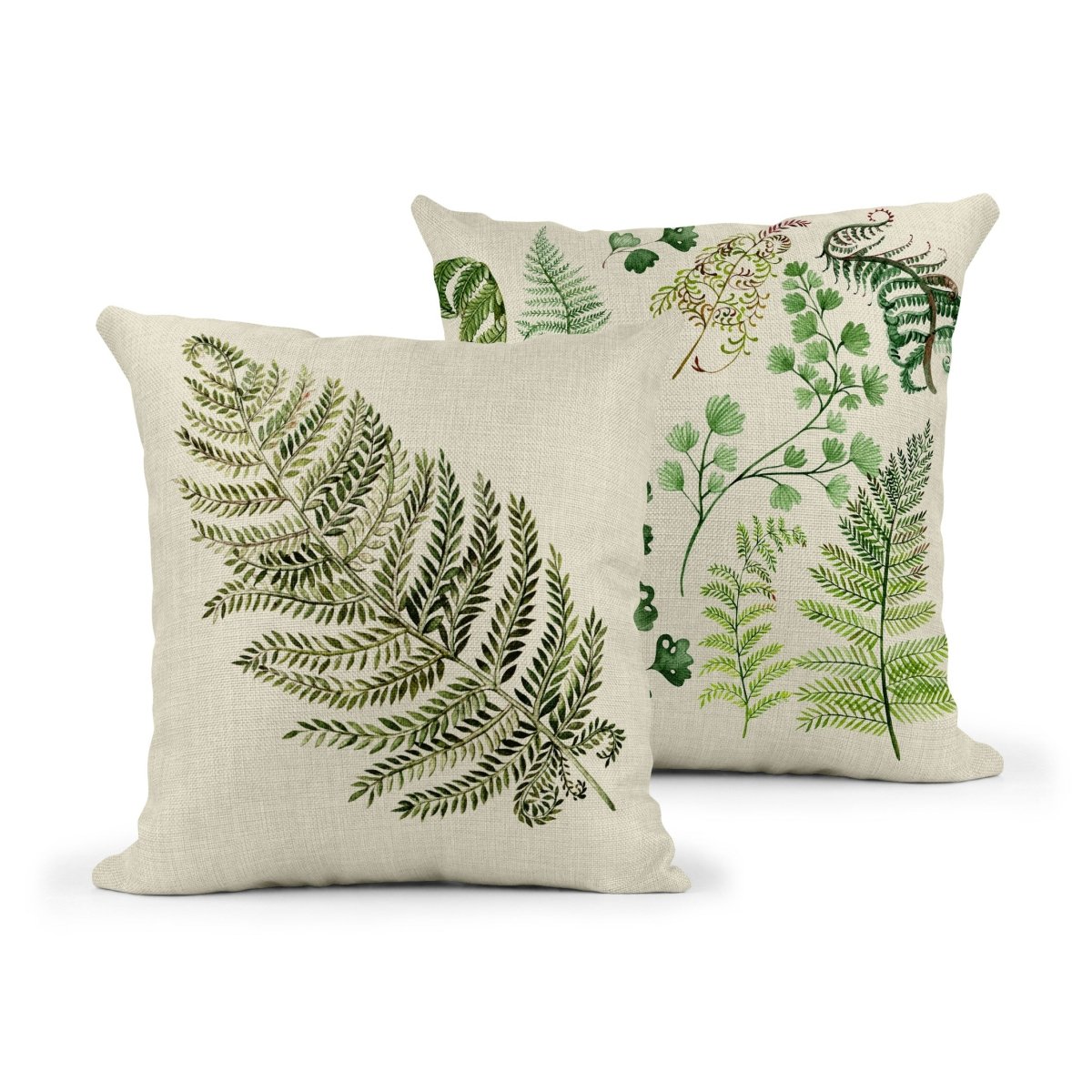 Two decorative throw pillows with a natural linen-coloured fabric, each featuring detailed green botanical fern illustrations. The front pillow shows a large single fern leaf, while the back pillow displays a variety of fern and leafy plant designs in different shades of green.