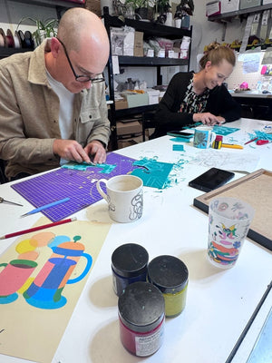 Two participants carving lino blocks during a relaxed jigsaw linocut workshop at the Mustard & Gray studio in Shropshire.