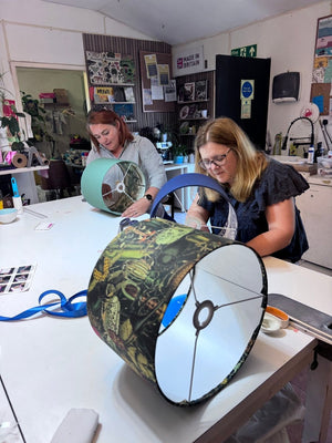 Two women making patterned drum lampshades during a Mustard & Gray lampshade-making workshop in Shropshire.