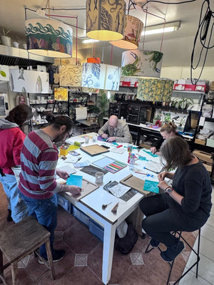 Small group carving lino blocks together around a table during a relaxed printmaking workshop at the Mustard & Gray studio in Shropshire.