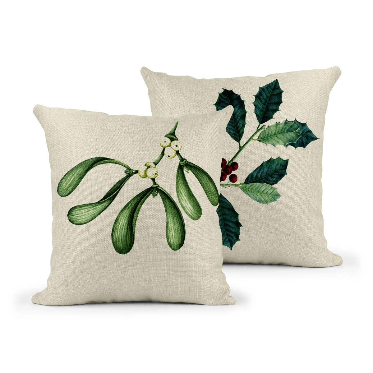 Pair of square linen-effect cushions featuring botanical Christmas designs. One cushion shows mistletoe with green leaves and white berries; the other displays holly with dark green spiky leaves and red berries, both on a neutral fabric background.
