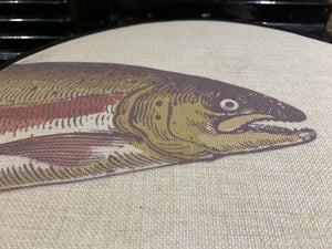 Close up image of printed salmon head in green and pink on a beige linen hob pad 