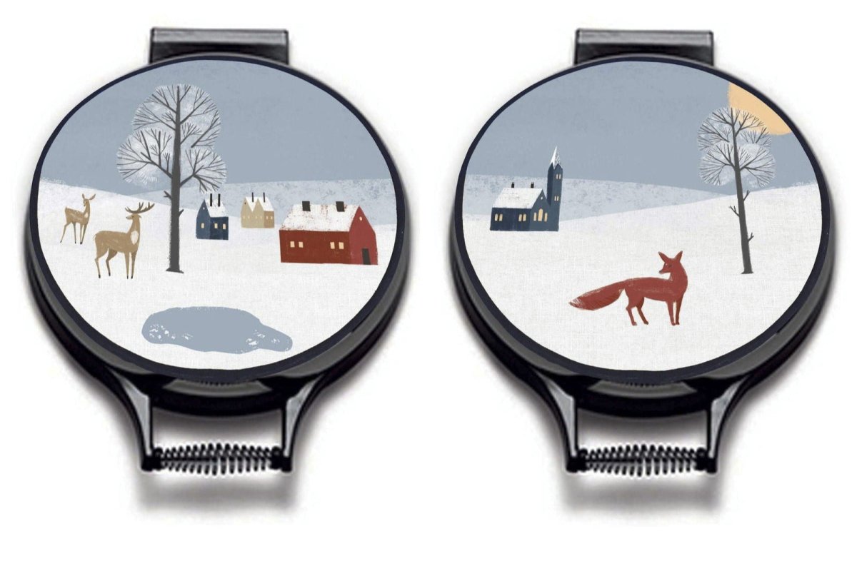Winter Fox Circular Hob Covers - Mustard and Gray Ltd “Two circular Aga, Stanley, Range stove covers with Scandi-inspired winter scenes. One features red houses, deer, and a snowy landscape; the other shows a red fox, bare trees, and a church under a winter sky.